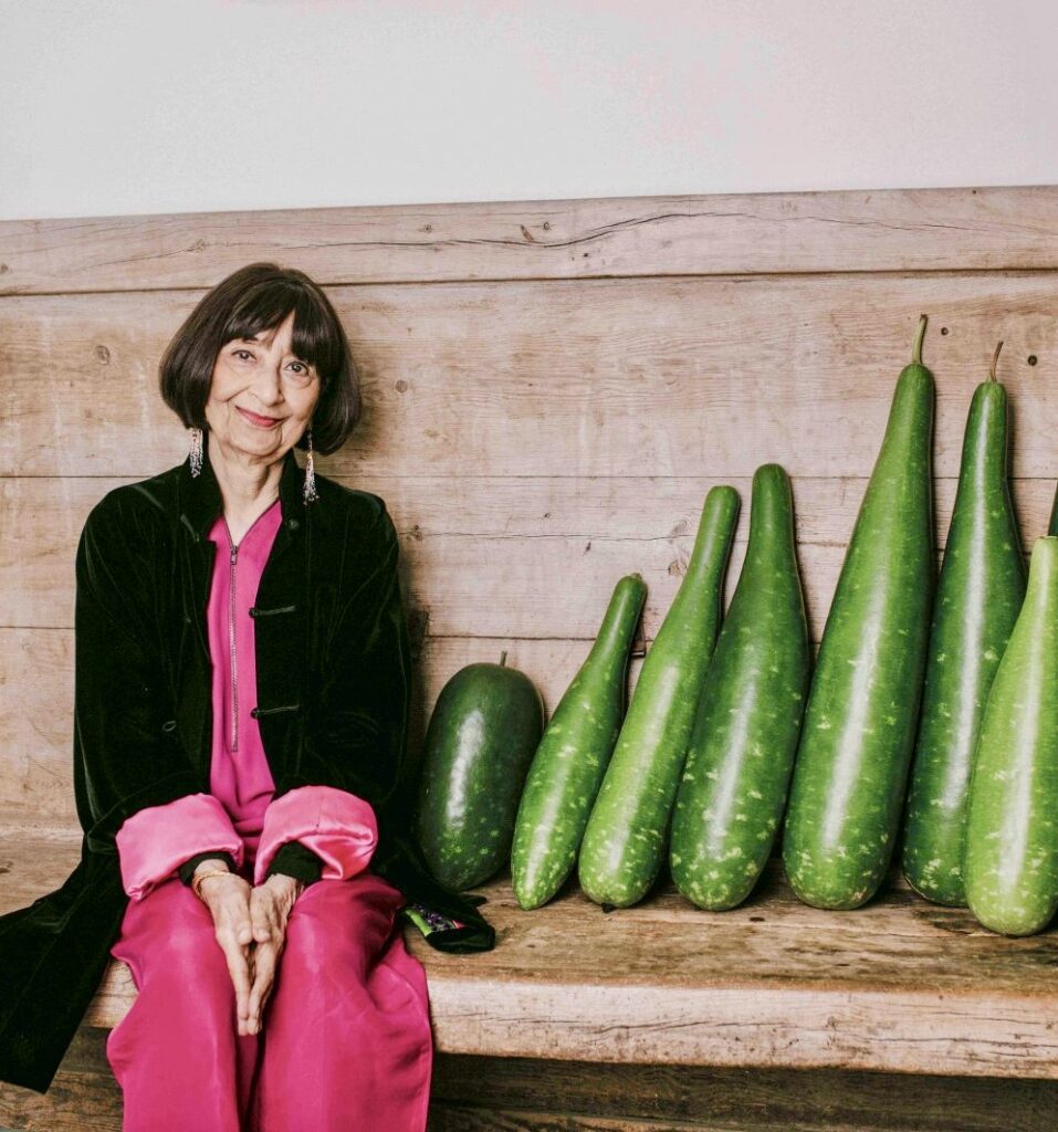 a person sitting next to a row of cucumbers