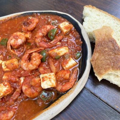 A bowl of shrimp and cheese with bread on a table