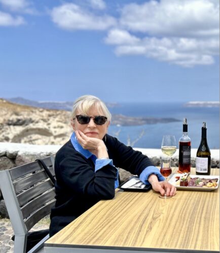 A woman sitting at a table with food and wine bottles