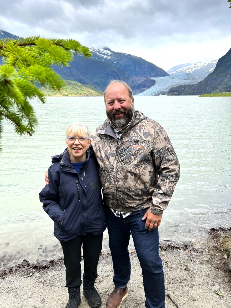 A man and woman standing next to each other in front of a lake
