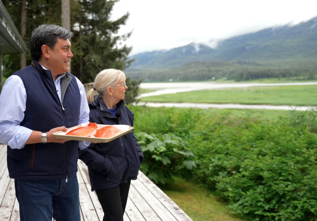 A man and woman holding a tray of fish