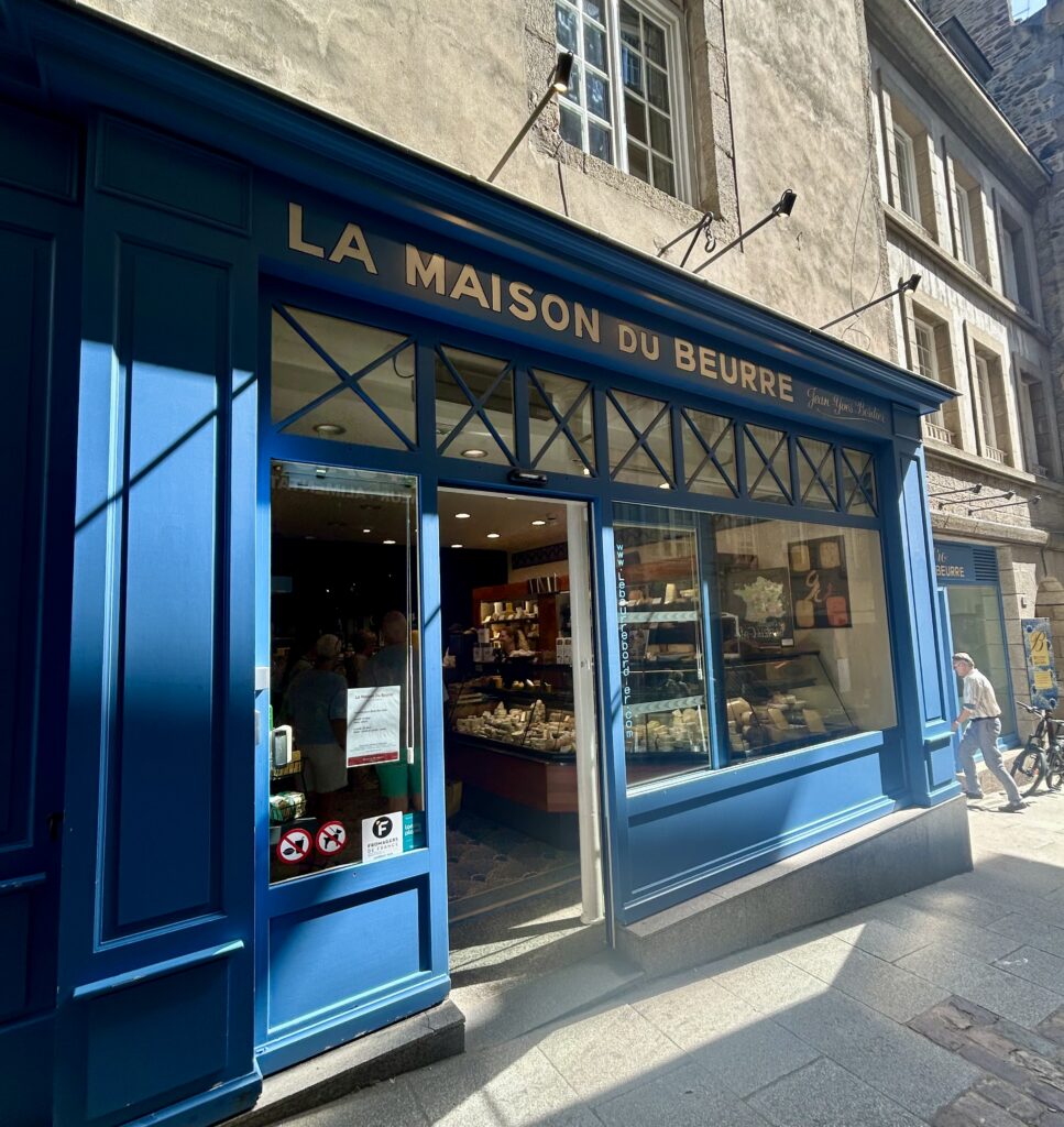 A blue store front with people walking on the sidewalk