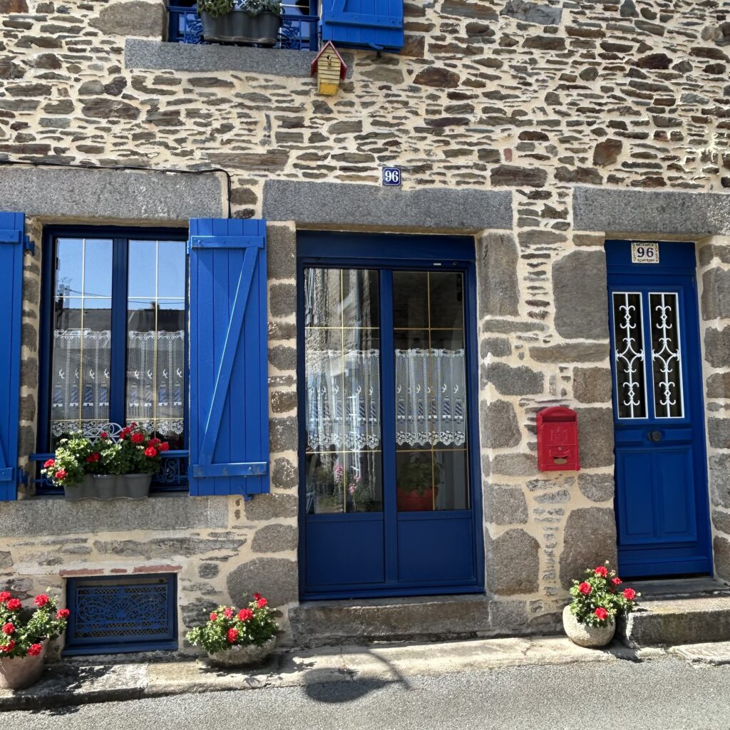 A stone building with blue shutters and flowers