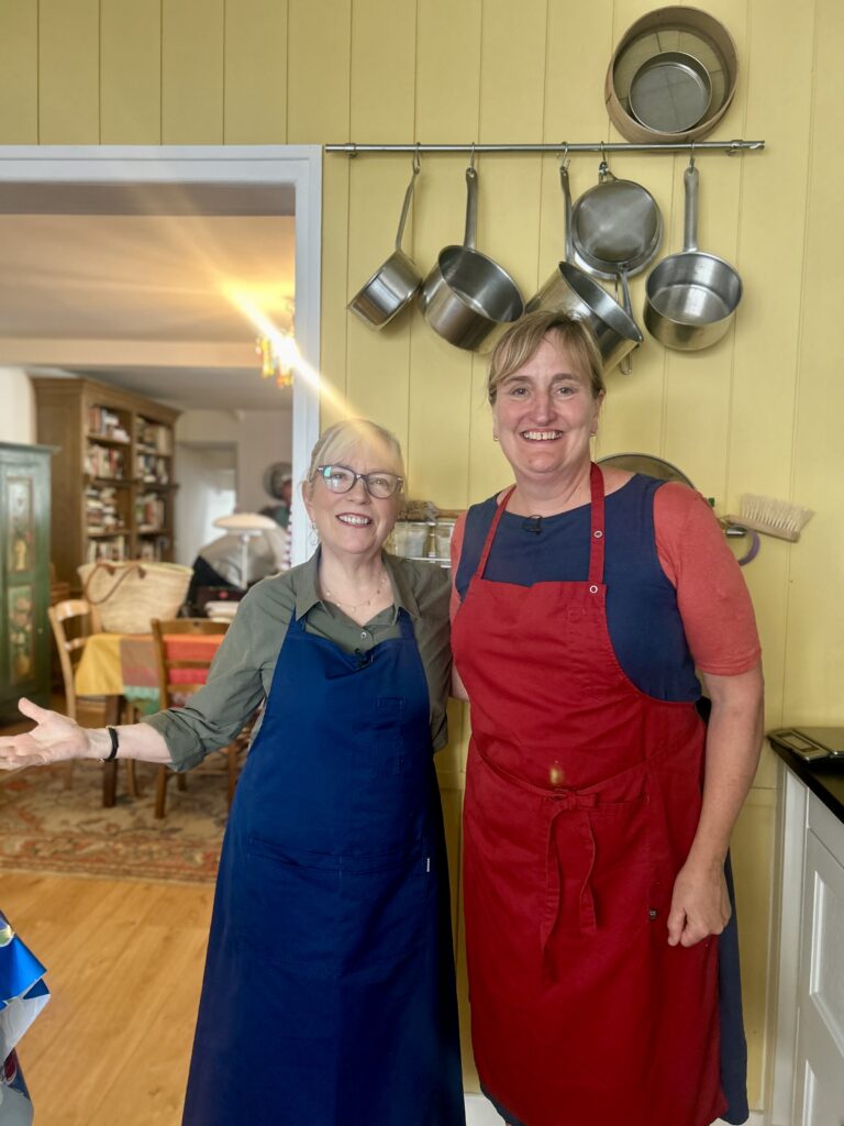 Two women wearing aprons in a kitchen
